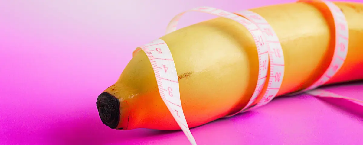 Penislengte mannen; banaan, ingewikkeld met meetlint op roze achtergrond